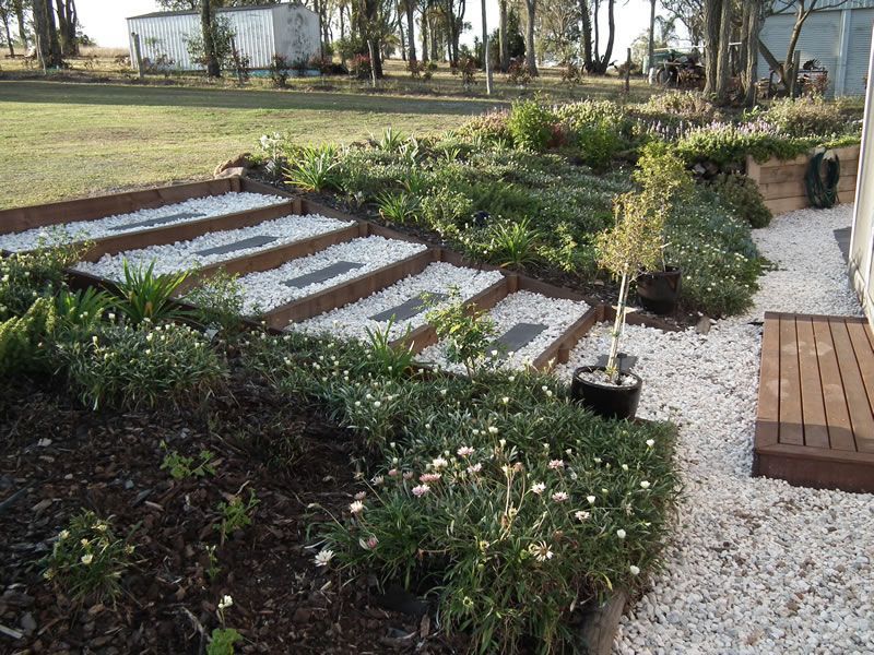 A garden with white gravel and steps leading up to a house
