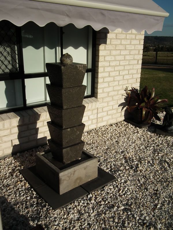 A brick house with a white awning and a fountain in front of it