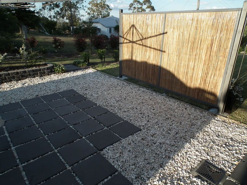 A bamboo fence is surrounded by gravel and black tiles