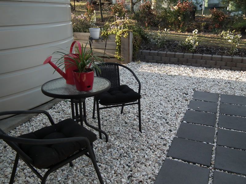 A red watering can sits on a table between two chairs