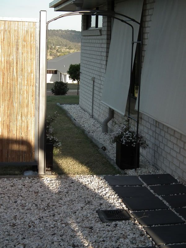 A brick house with a wooden fence and gravel in front of it