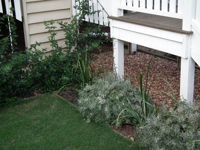A white veranda with a bench and plants in front of it