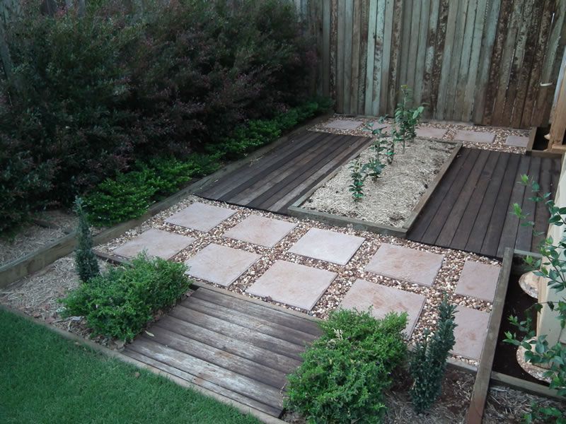 A backyard with a wooden walkway and a fence