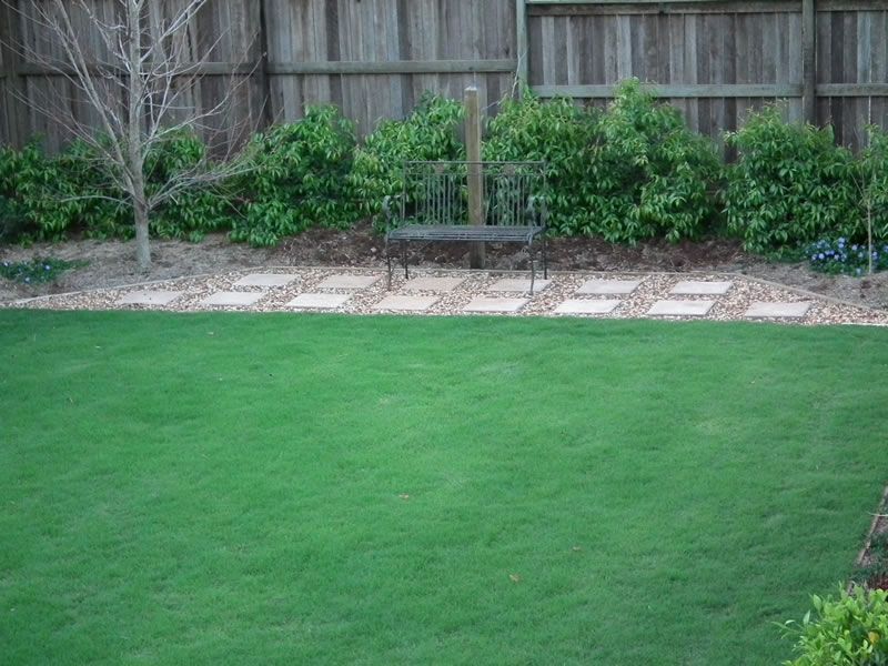 A lush green lawn with a wooden fence in the background