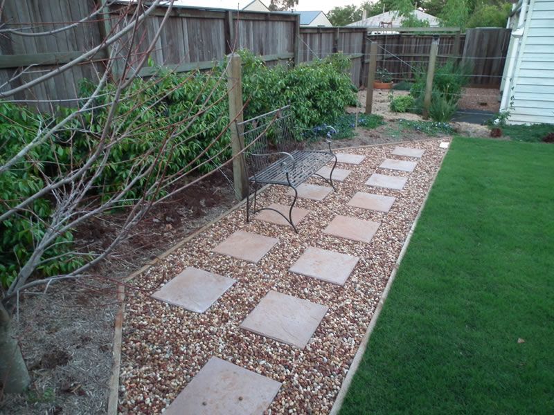 A fenced in yard with a bench and stepping stones