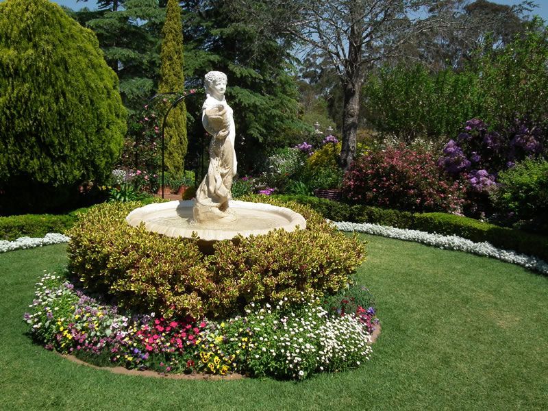 A fountain in a garden with flowers and bushes around it