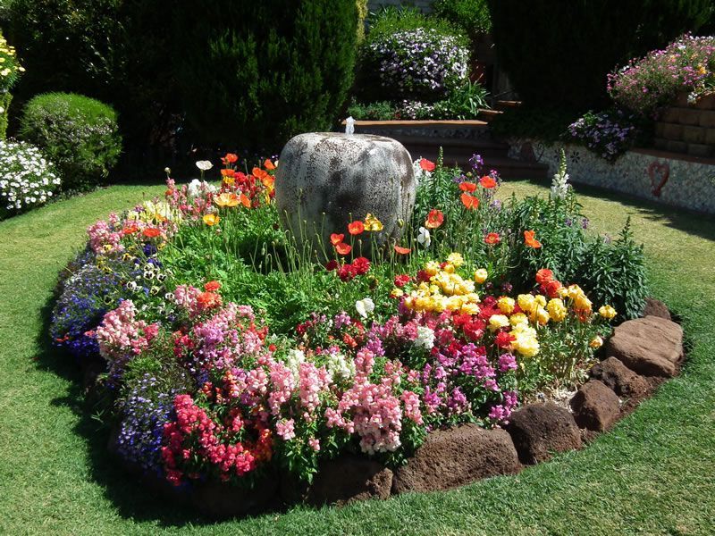 A garden with flowers and a fountain in the middle