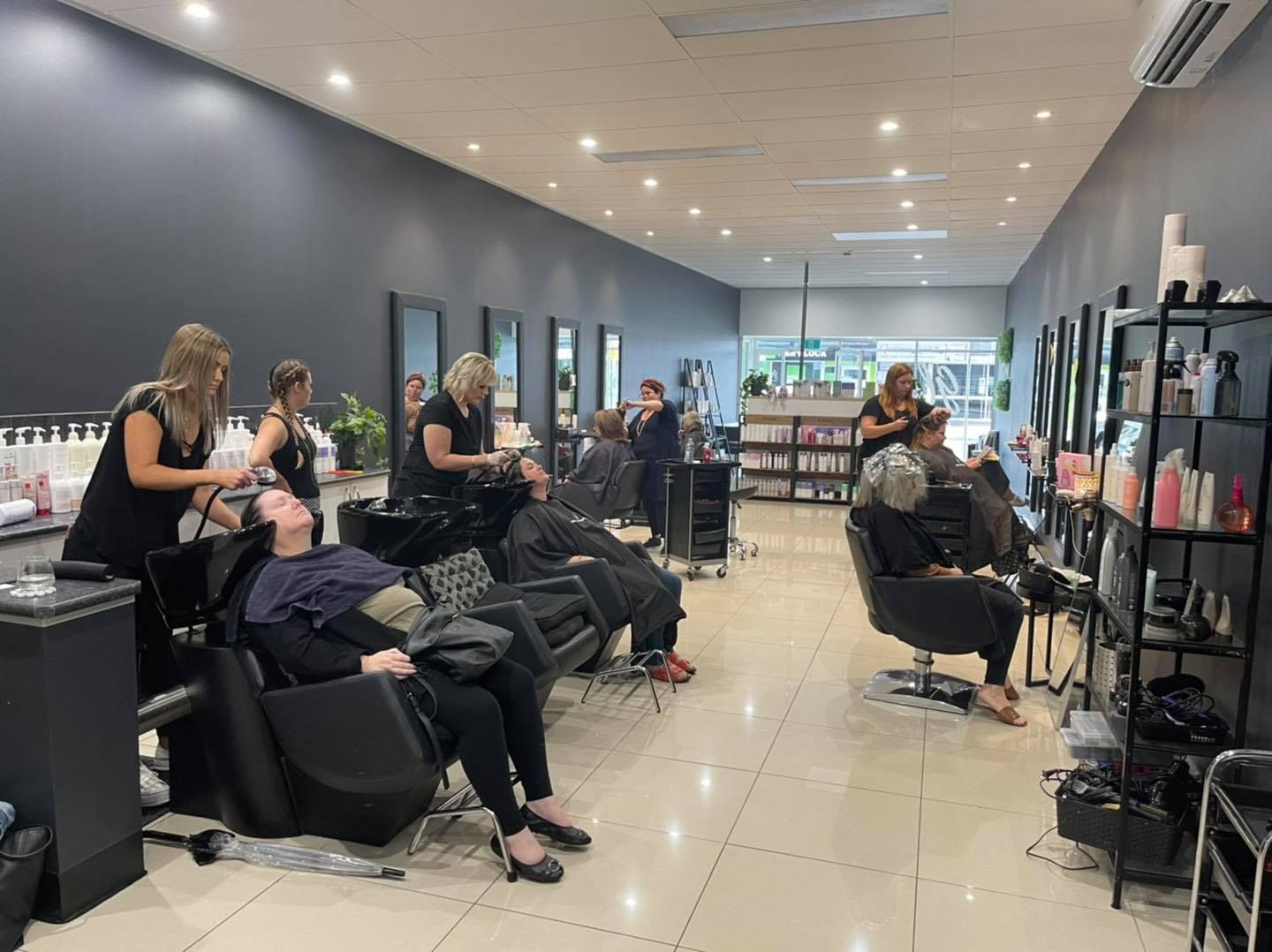 A woman wearing a mask is applying makeup to another woman 's face — Glam Hair and Beauty in Woy Woy, NSW