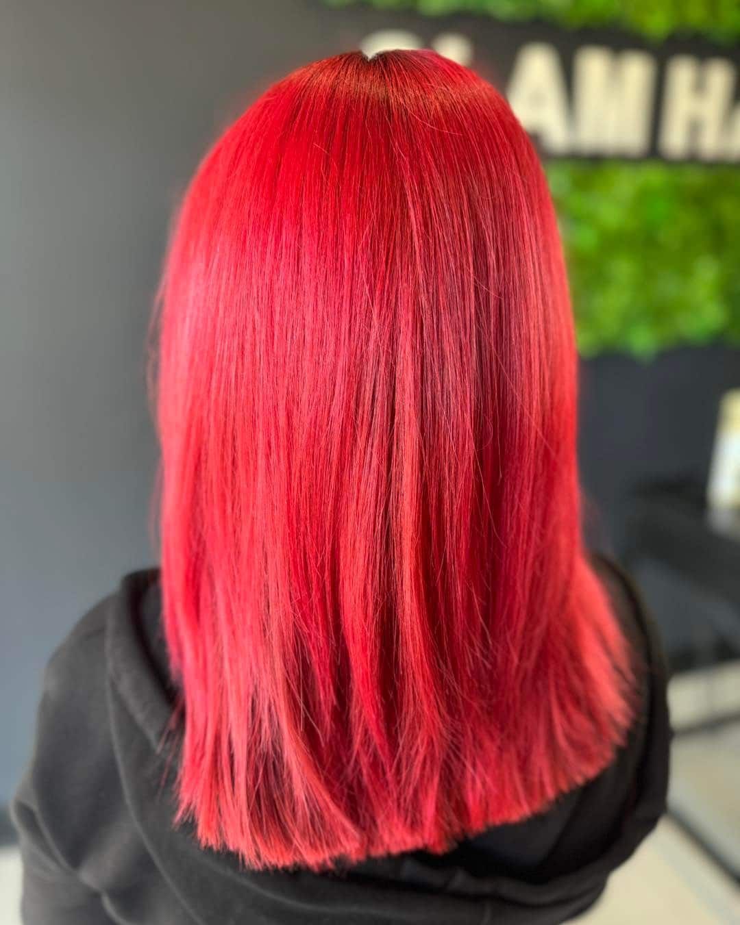A Woman With Bright Red Hair is Wearing a Black Hoodie — Glam Hair and Beauty in Woy Woy, NSW