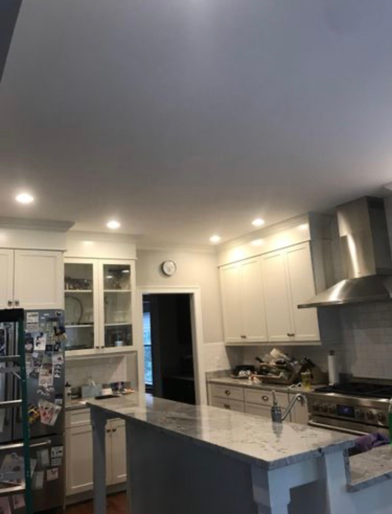 A kitchen with white cabinets , stainless steel appliances , and a large island.