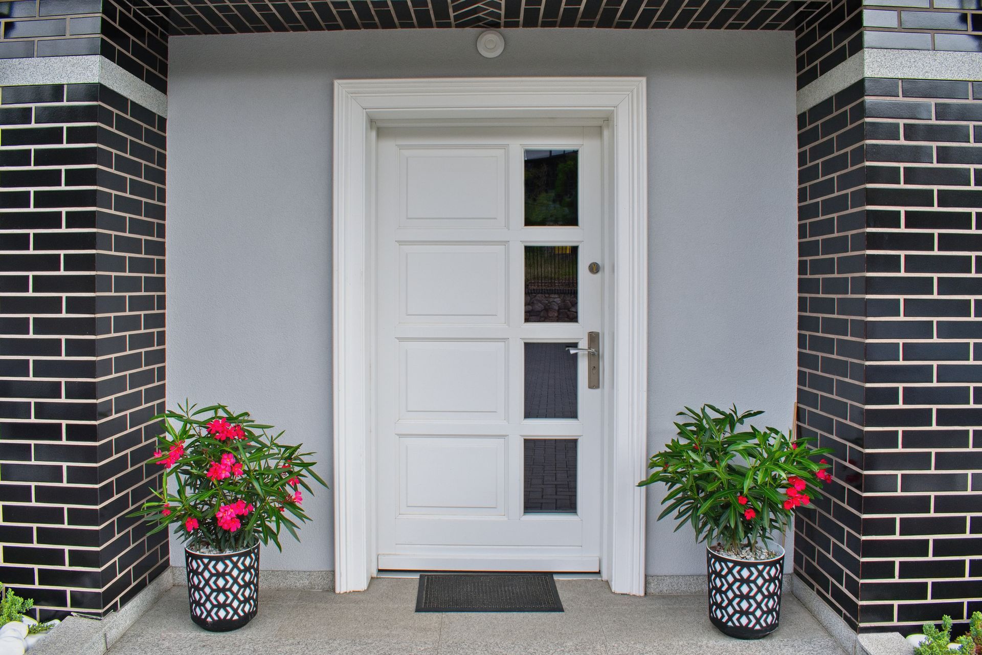 A white door with two potted plants in front of it