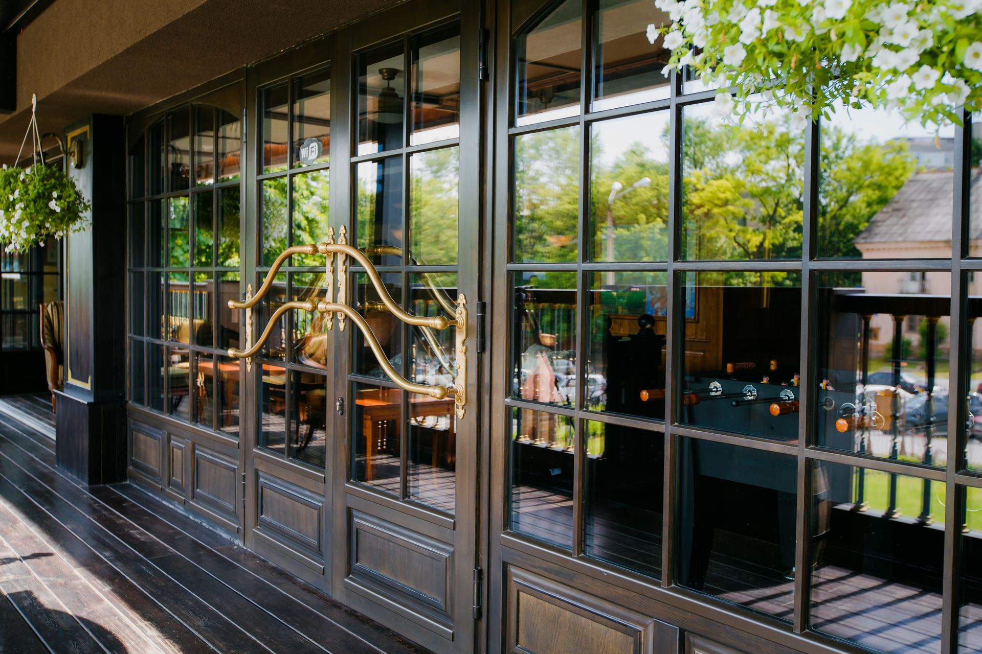 A restaurant with a lot of windows and flowers hanging from the ceiling.