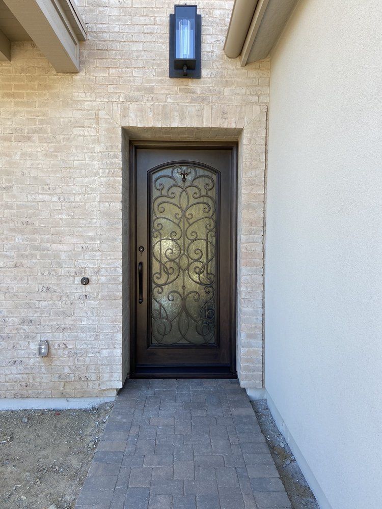 A brick building with a wrought iron door and a brick walkway