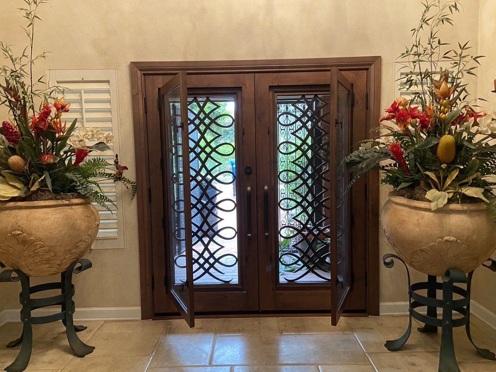 A hallway with two potted plants in front of a door.