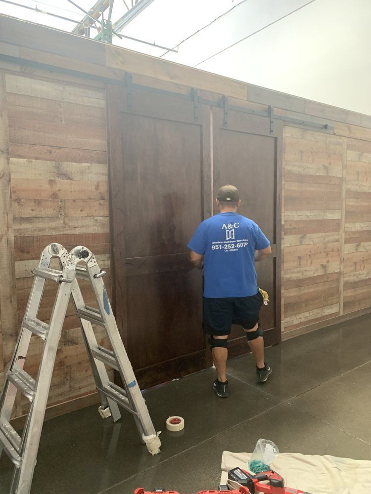A man in a blue shirt is painting a barn door.