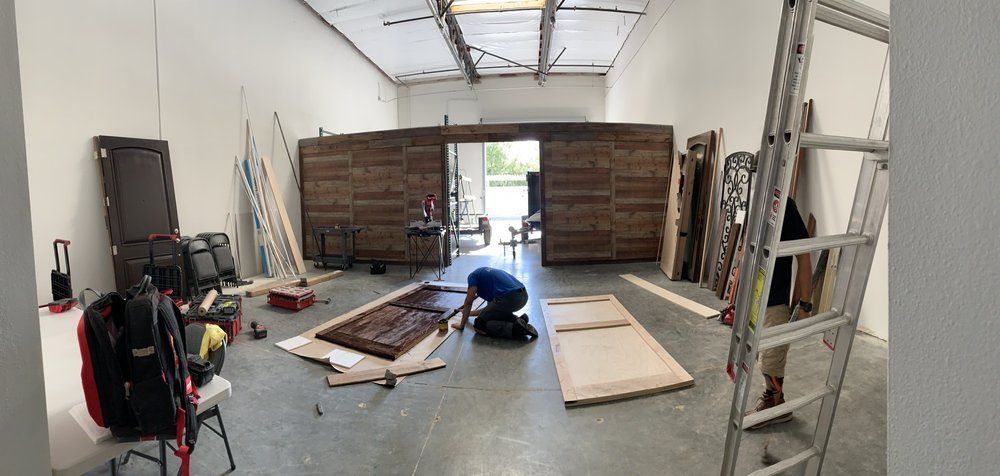 A man is kneeling down in a room with a ladder.