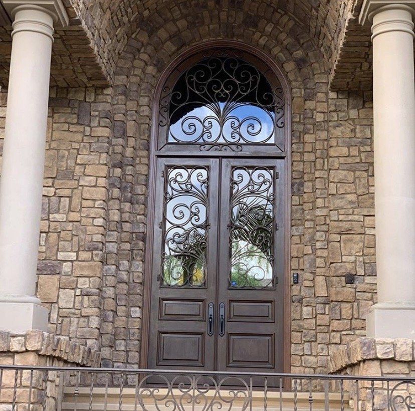 The front door of a brick building has a wrought iron arch above it