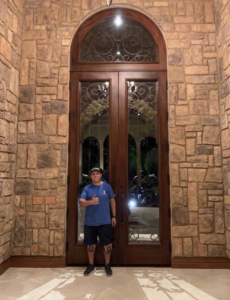 A man in a blue shirt is standing in front of a large door.