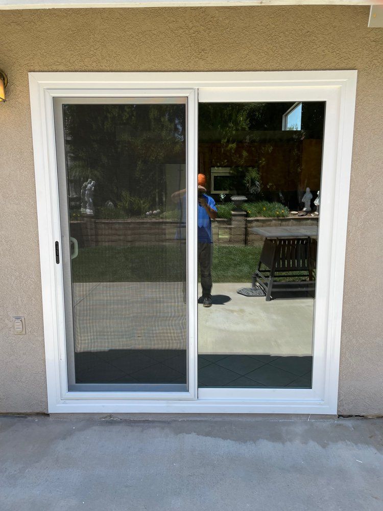 A man is standing in front of a sliding glass door.