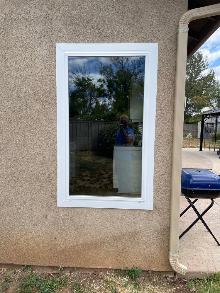 A white window is on the side of a house.