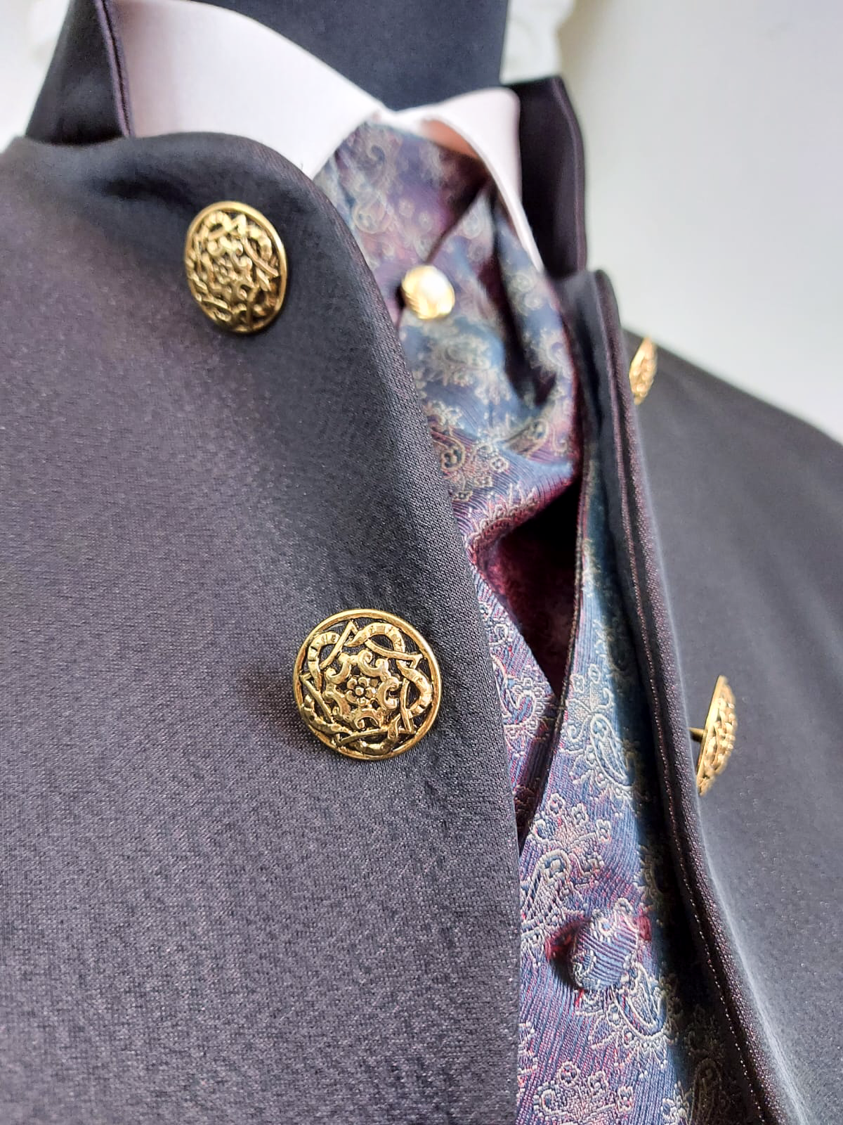 Un primo piano della giacca di un uomo con bottoni dorati