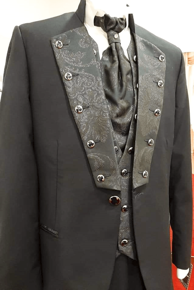 Un uomo indossa uno smoking nero e una cravatta su un manichino.