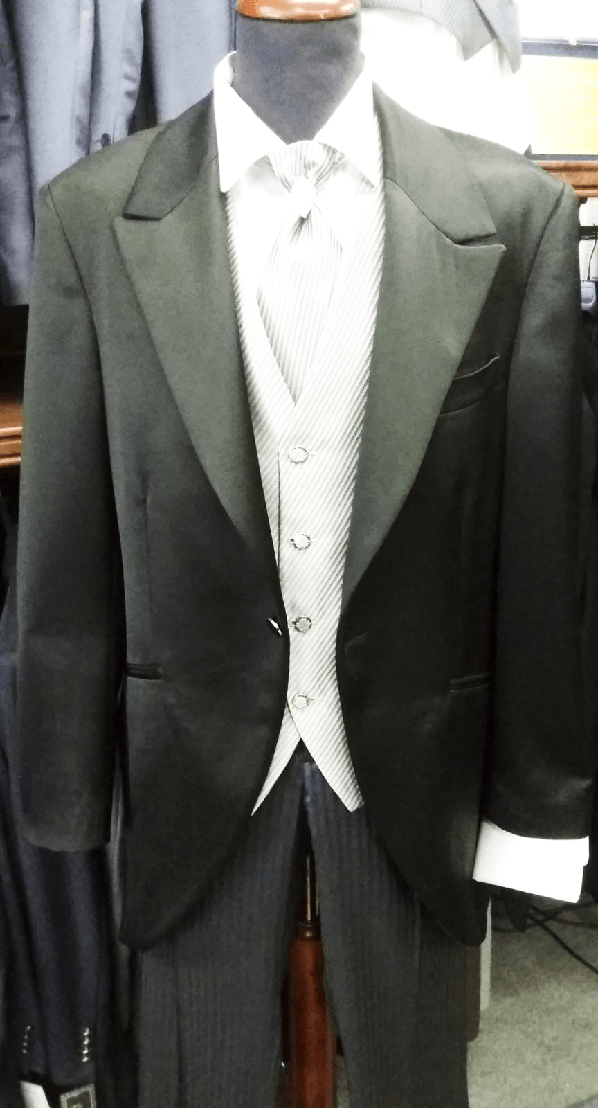 Uno smoking nero con gilet bianco e cravatta è su un manichino