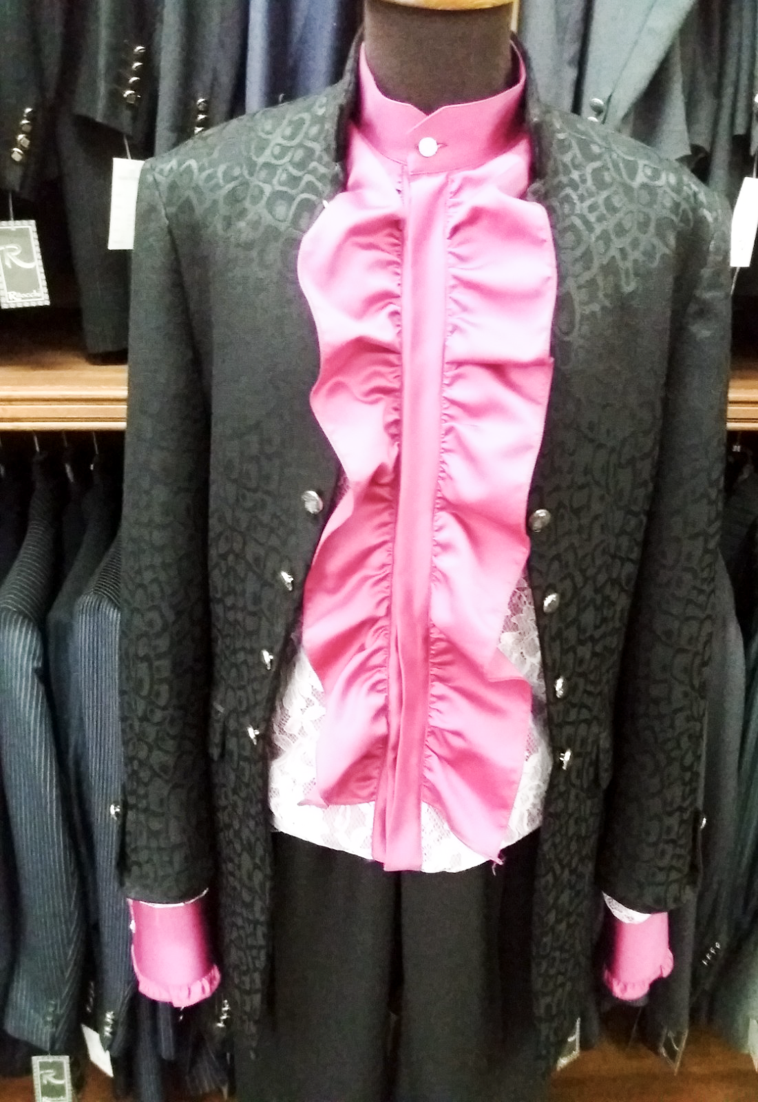 Un manichino indossa un abito nero e una camicia rosa con volant
