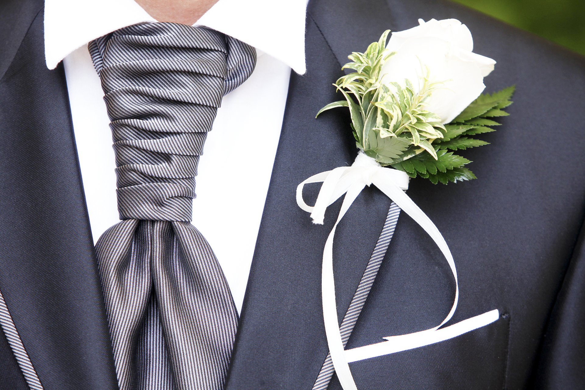 Un uomo in giacca e cravatta ha una rosa bianca in tasca