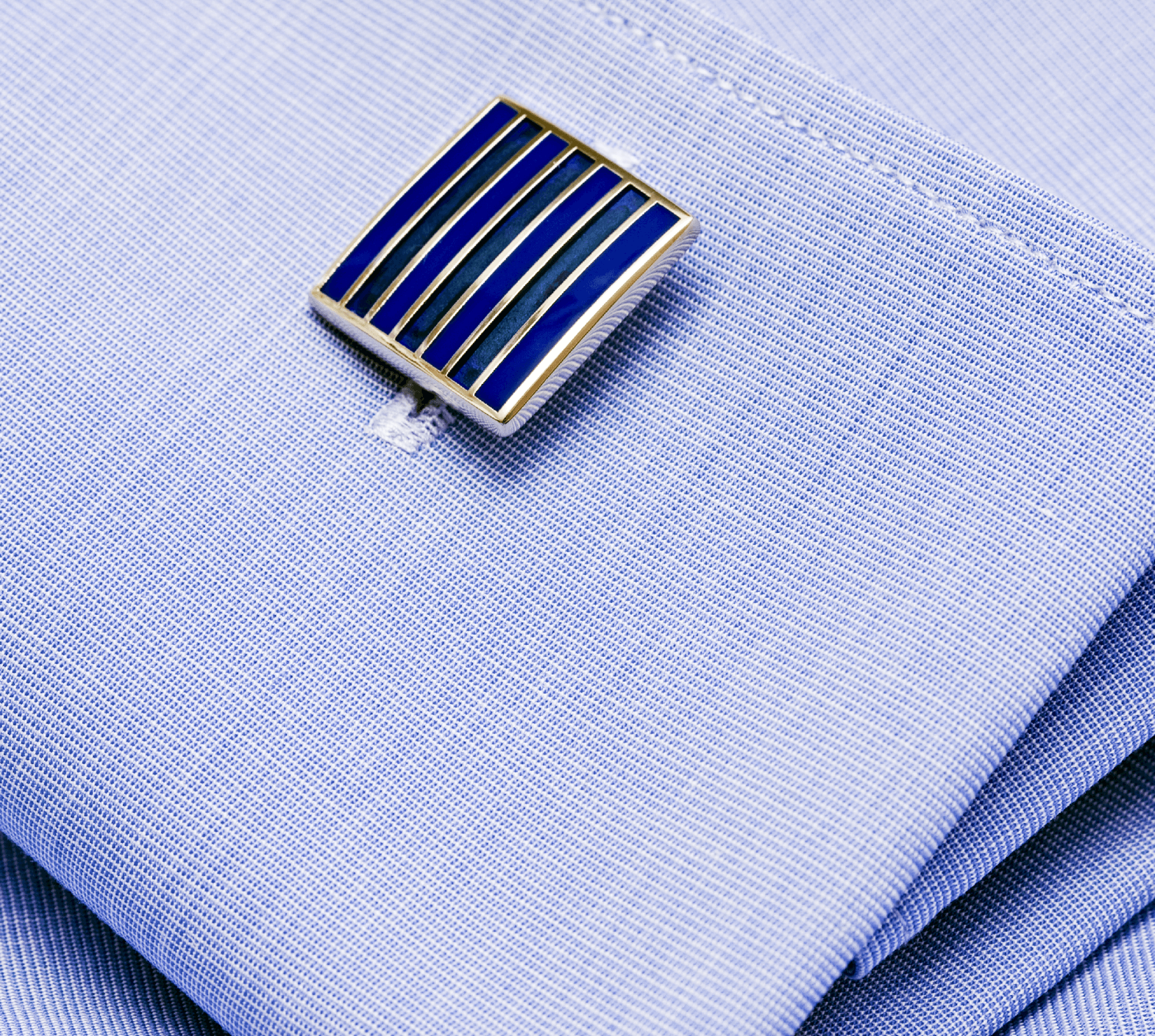 Primo piano di un paio di gemelli su una camicia blu.