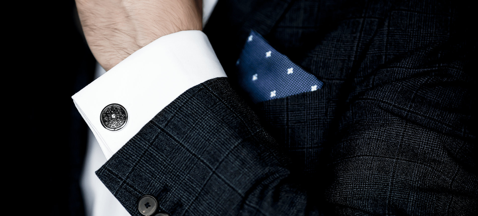 Un uomo che indossa un abito e gemelli ha un fazzoletto da taschino nel taschino.