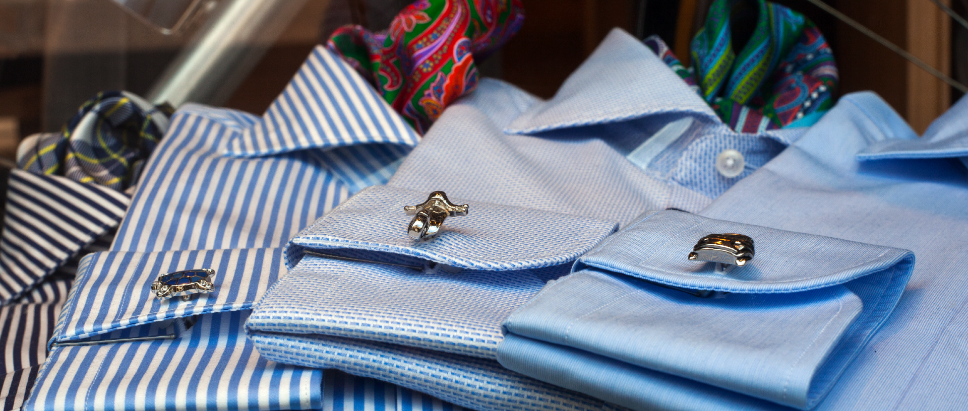 Una pila di camicie a righe blu con gemelli e cravatte.