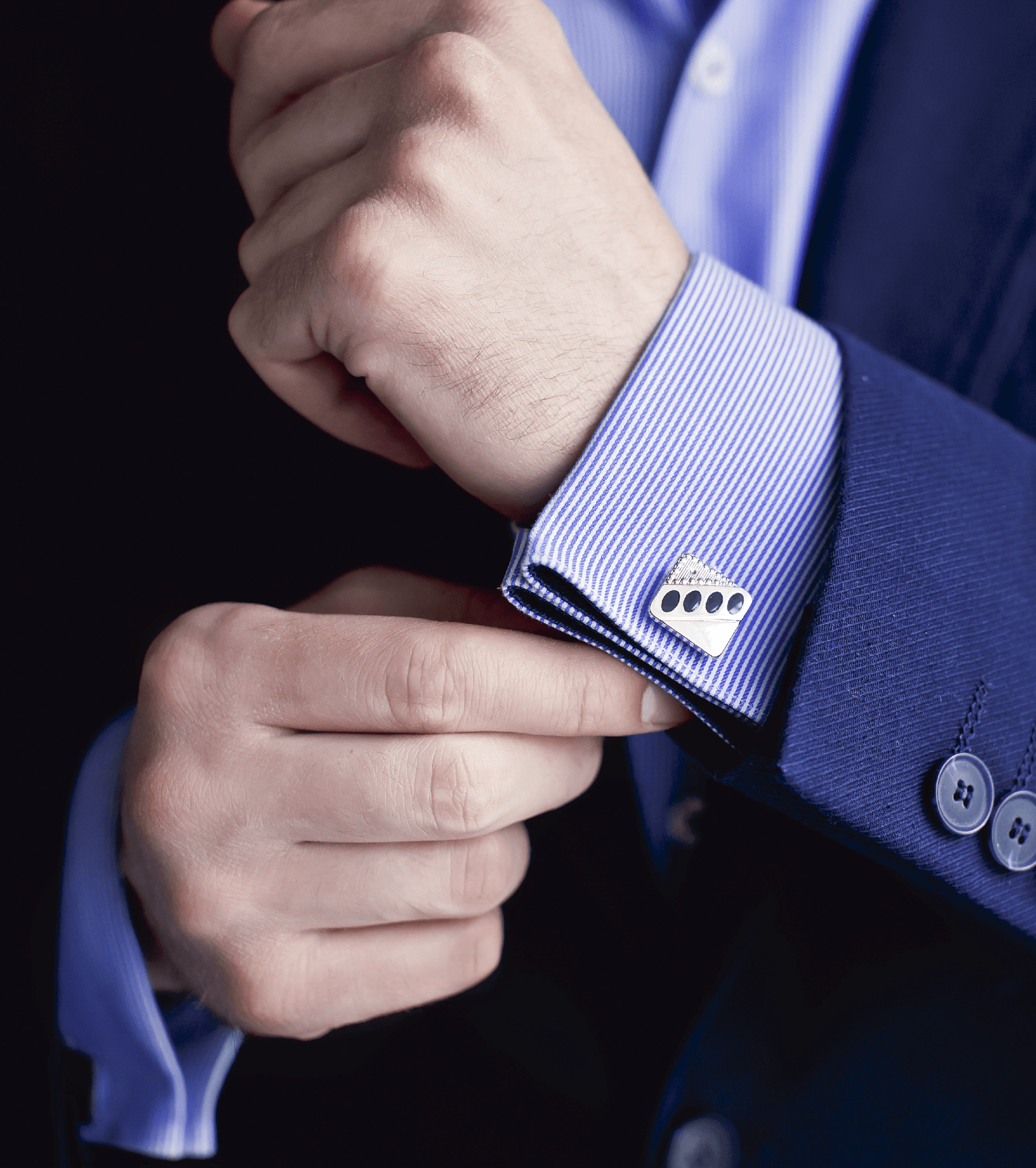 Un uomo in giacca e cravatta si sta sistemando i gemelli