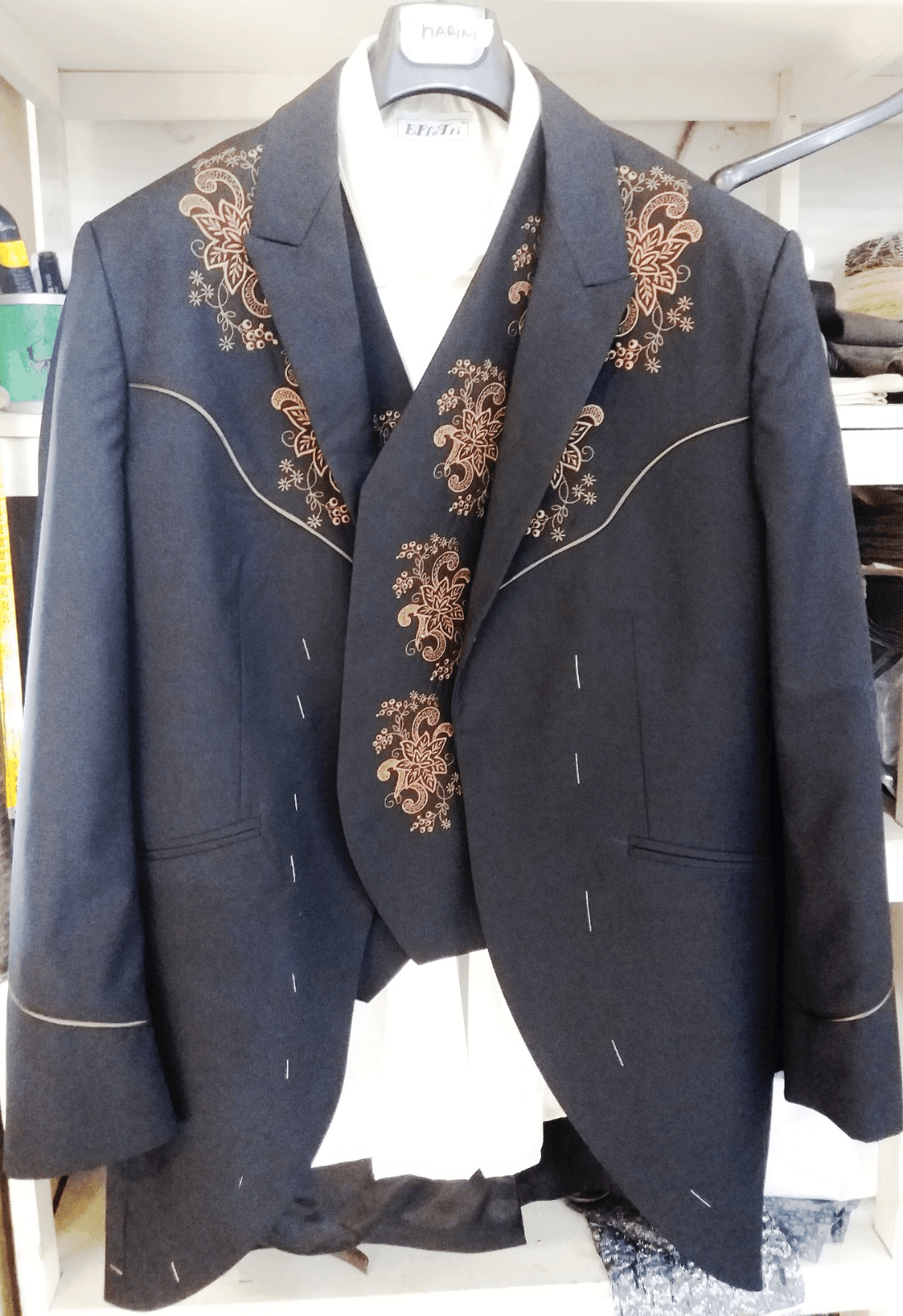 Un abito nero con ricami marroni è appeso a una gruccia