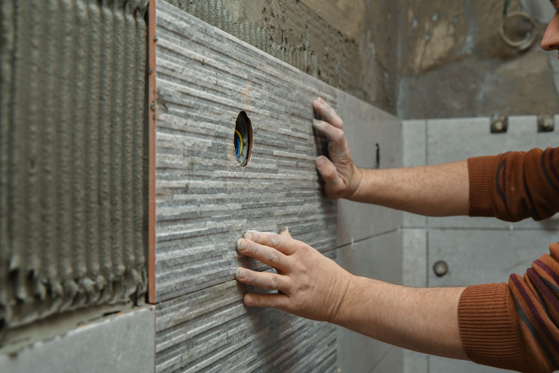 Mani intente a installare un pannello murale ondulato grigio con un'apertura circolare in un cantiere edile.