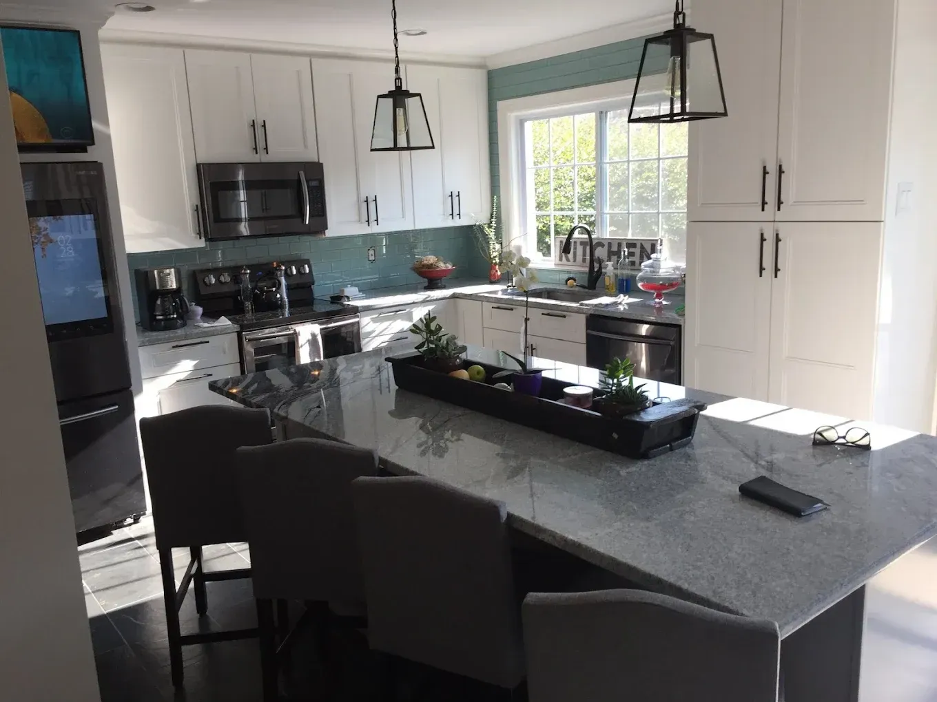 Modern kitchen with white cabinets, a large island, and a light blue backsplash.