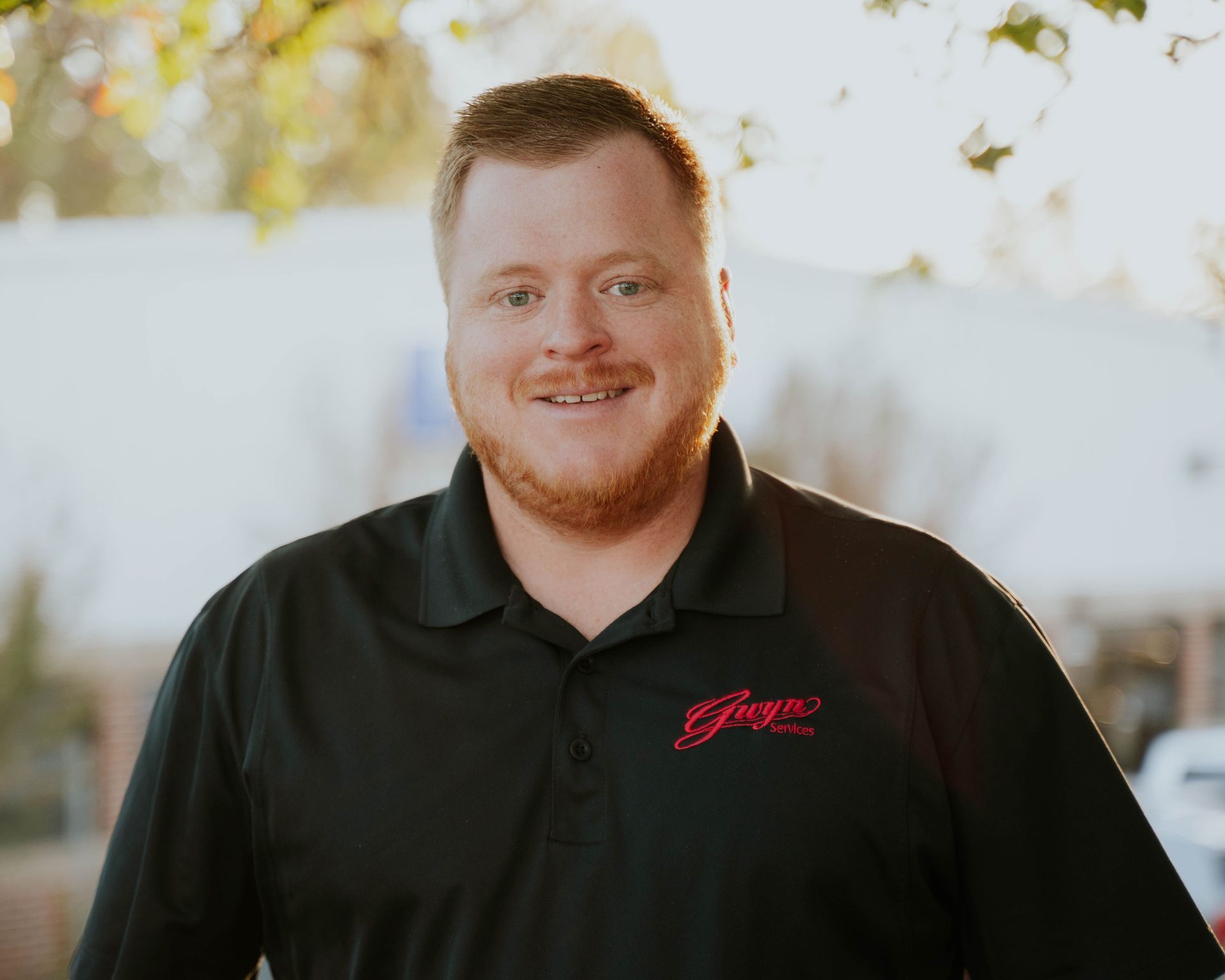 A bald man with a beard and glasses is wearing a black shirt.