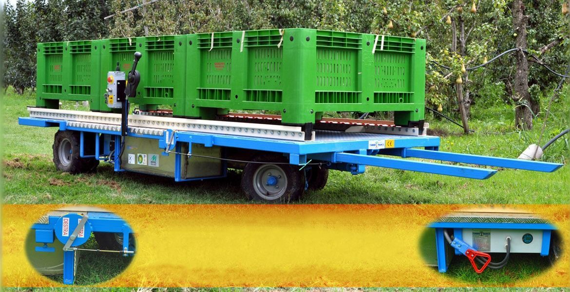 Rimorchio blu e bianco che trasporta tre bidoni verdi, probabilmente utilizzati per la raccolta agricola.