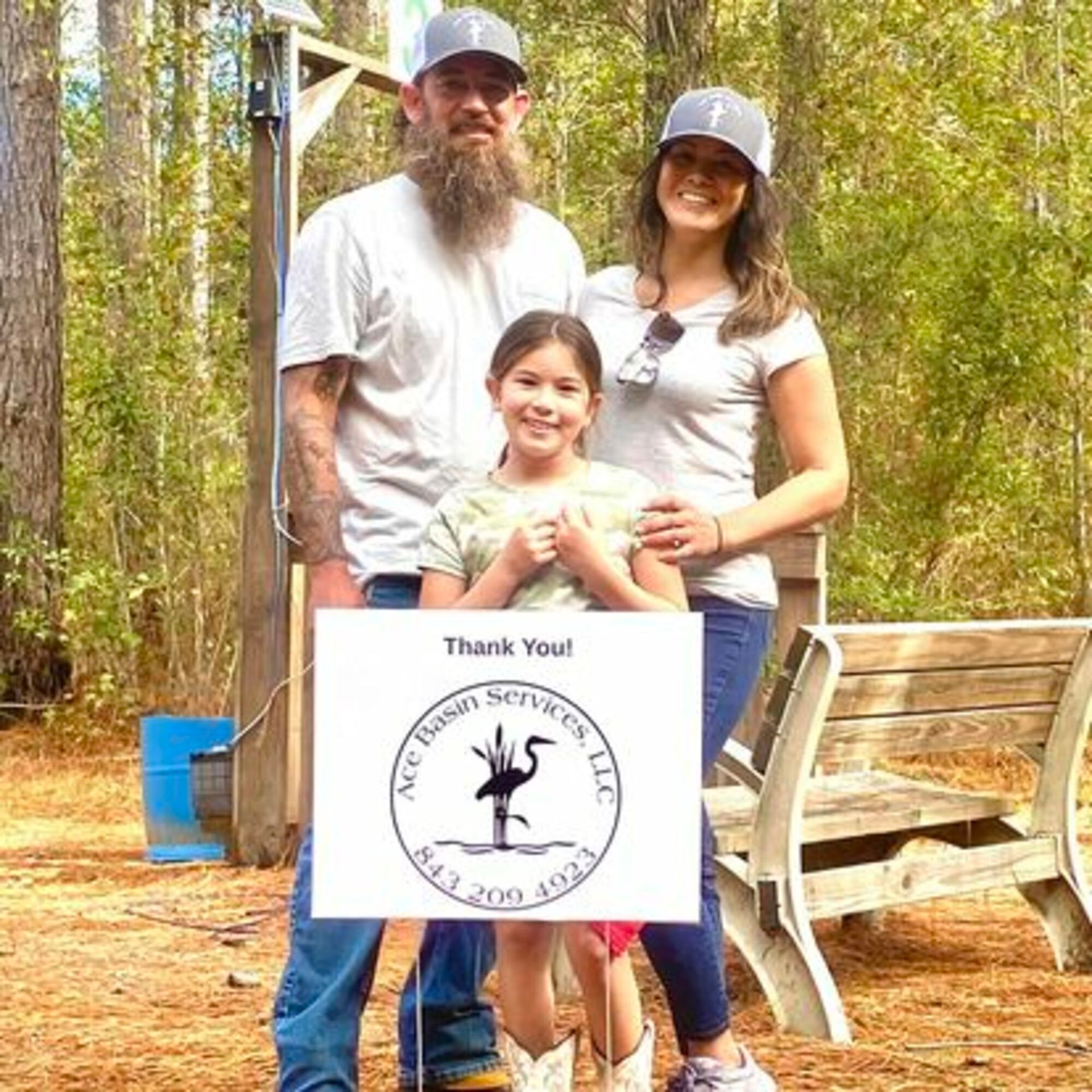 A man , woman and child are holding a thank you sign.