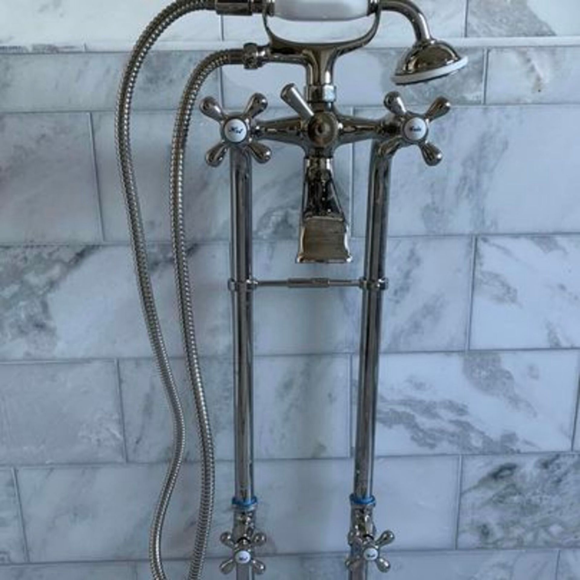 A faucet with a hose attached to it is hanging on a marble wall.