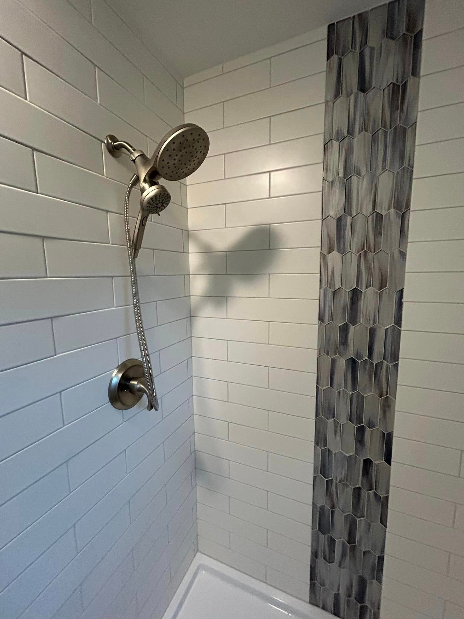 There is a shower head in the corner of the bathroom.