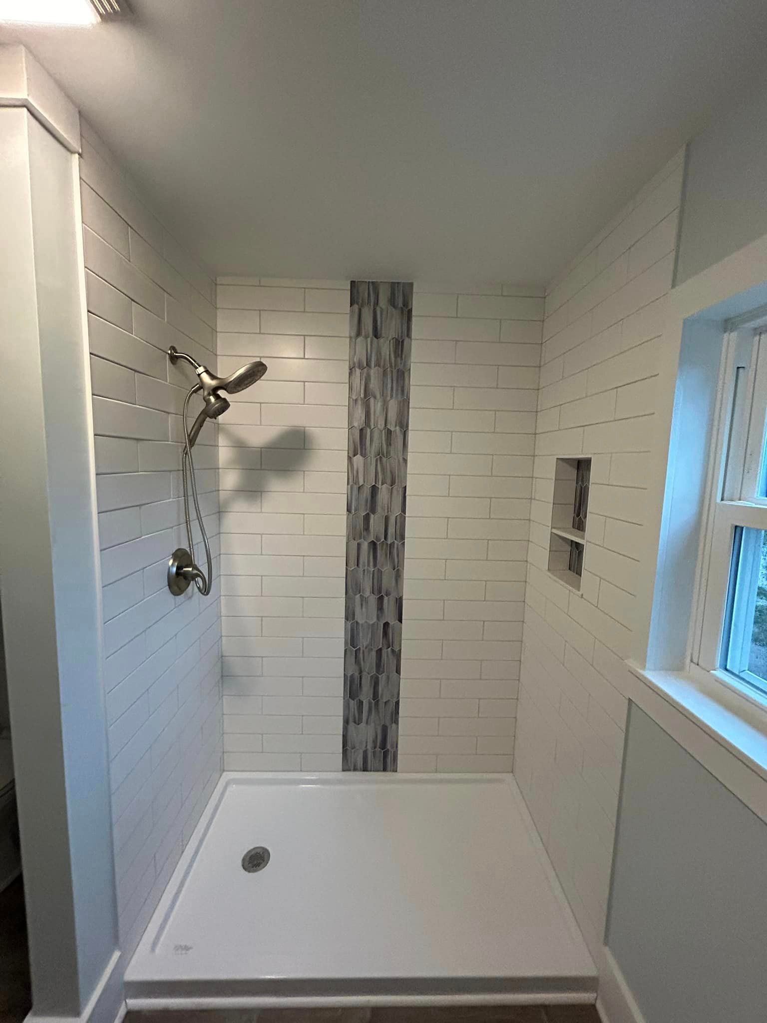 A bathroom with a walk in shower and a window.