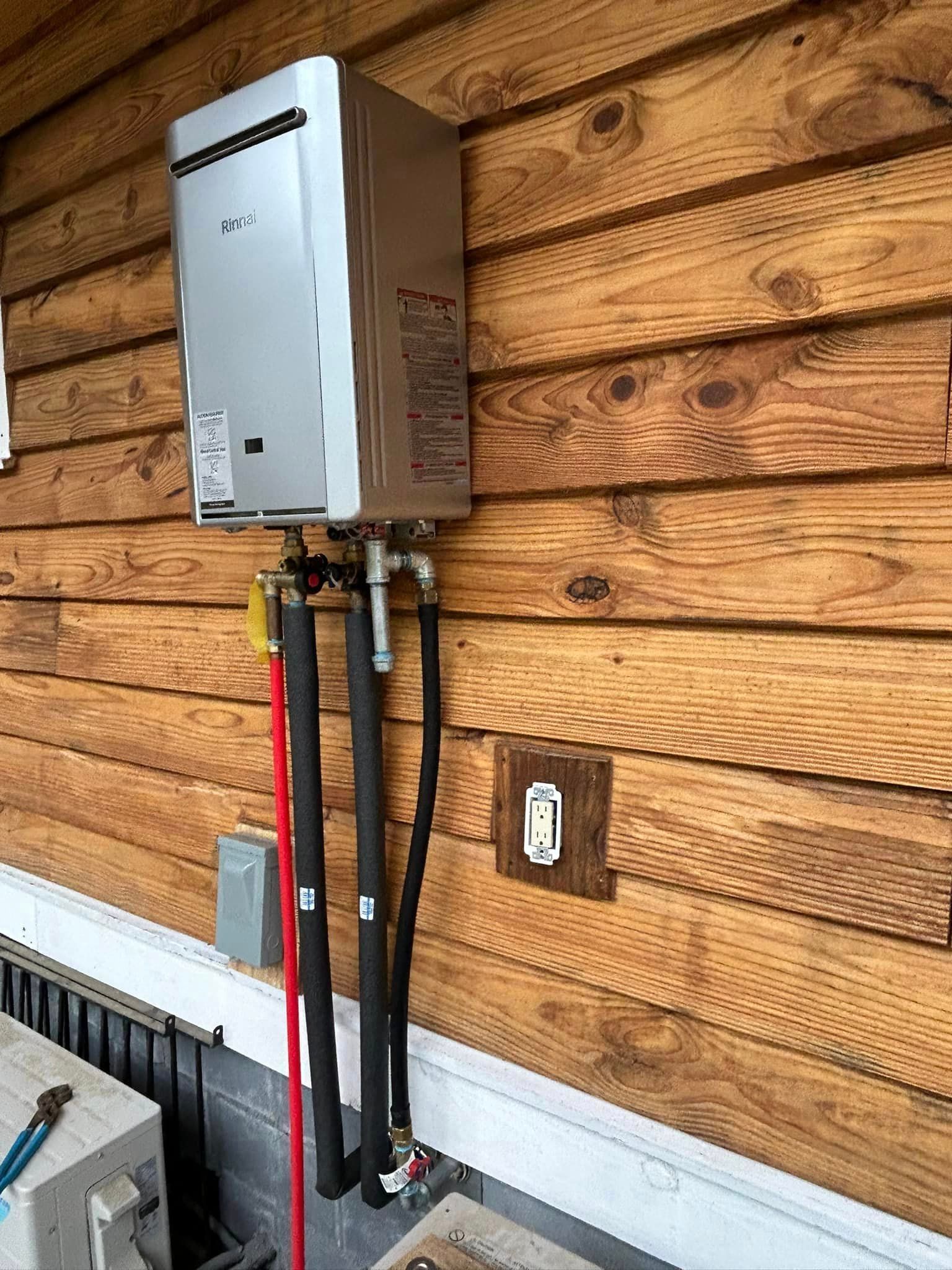 A stainless steel water heater is attached to a wooden wall.