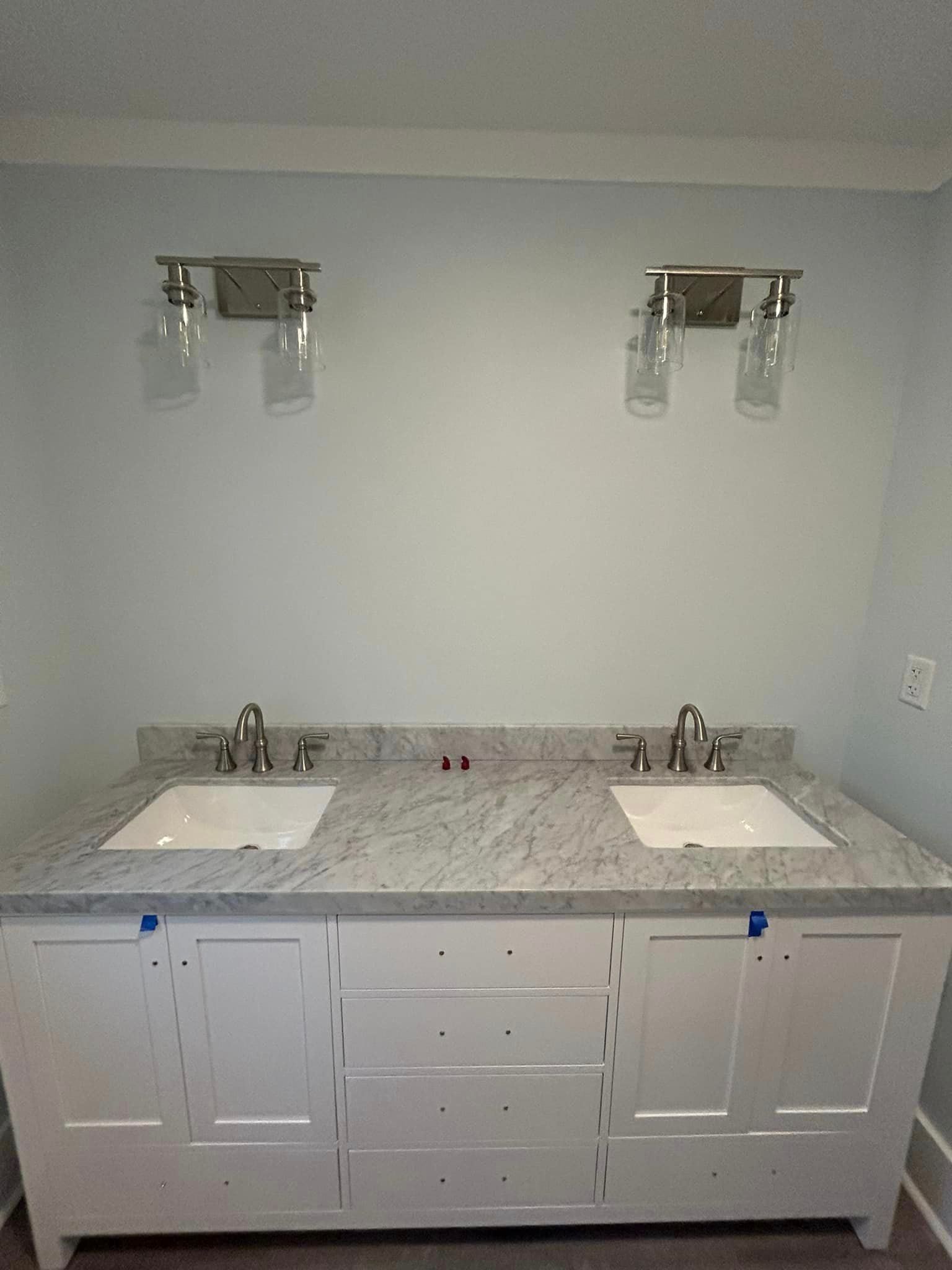A bathroom with two sinks and two lights on the wall.