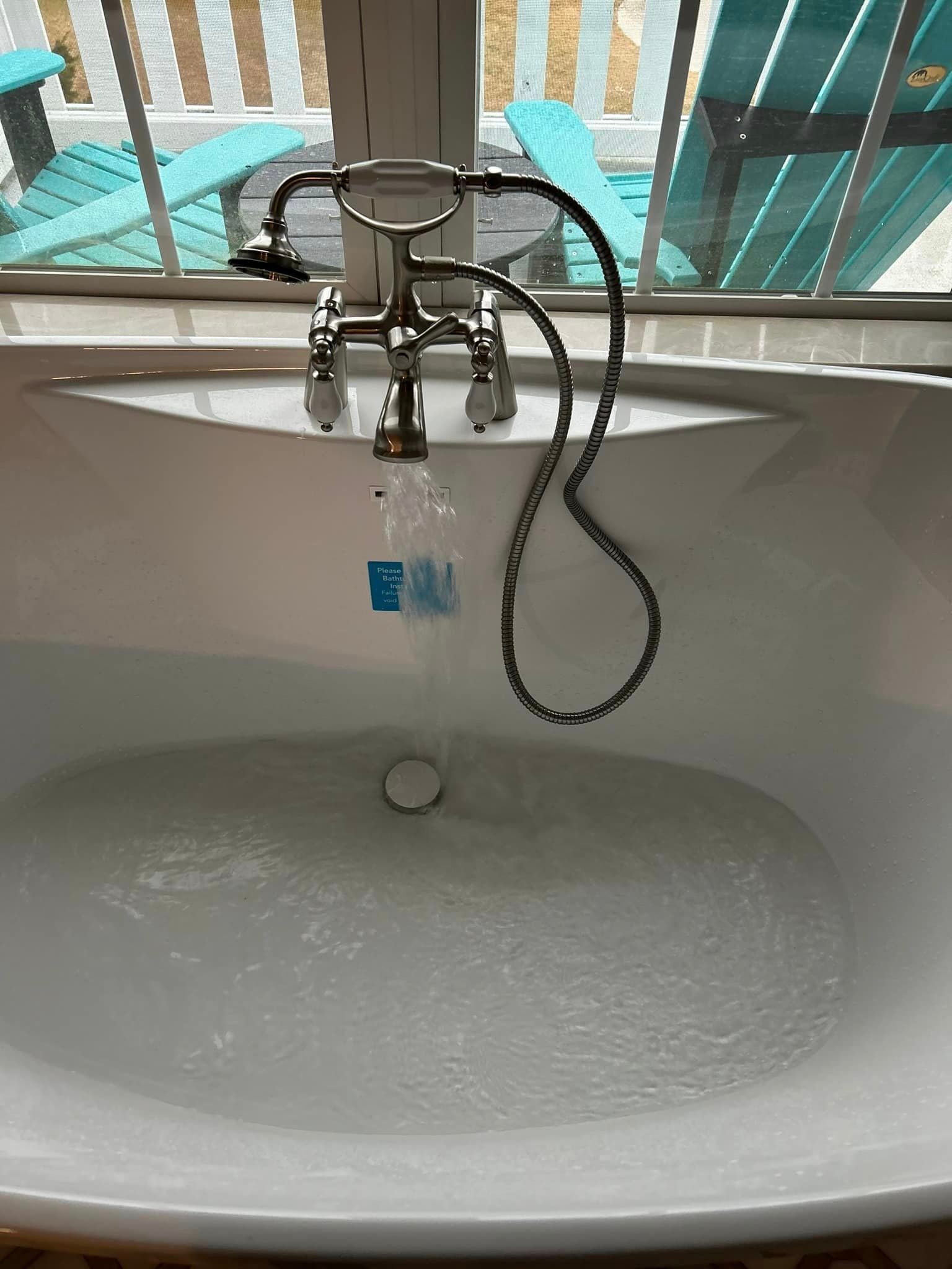 A bathtub with a shower head attached to it is filled with water.