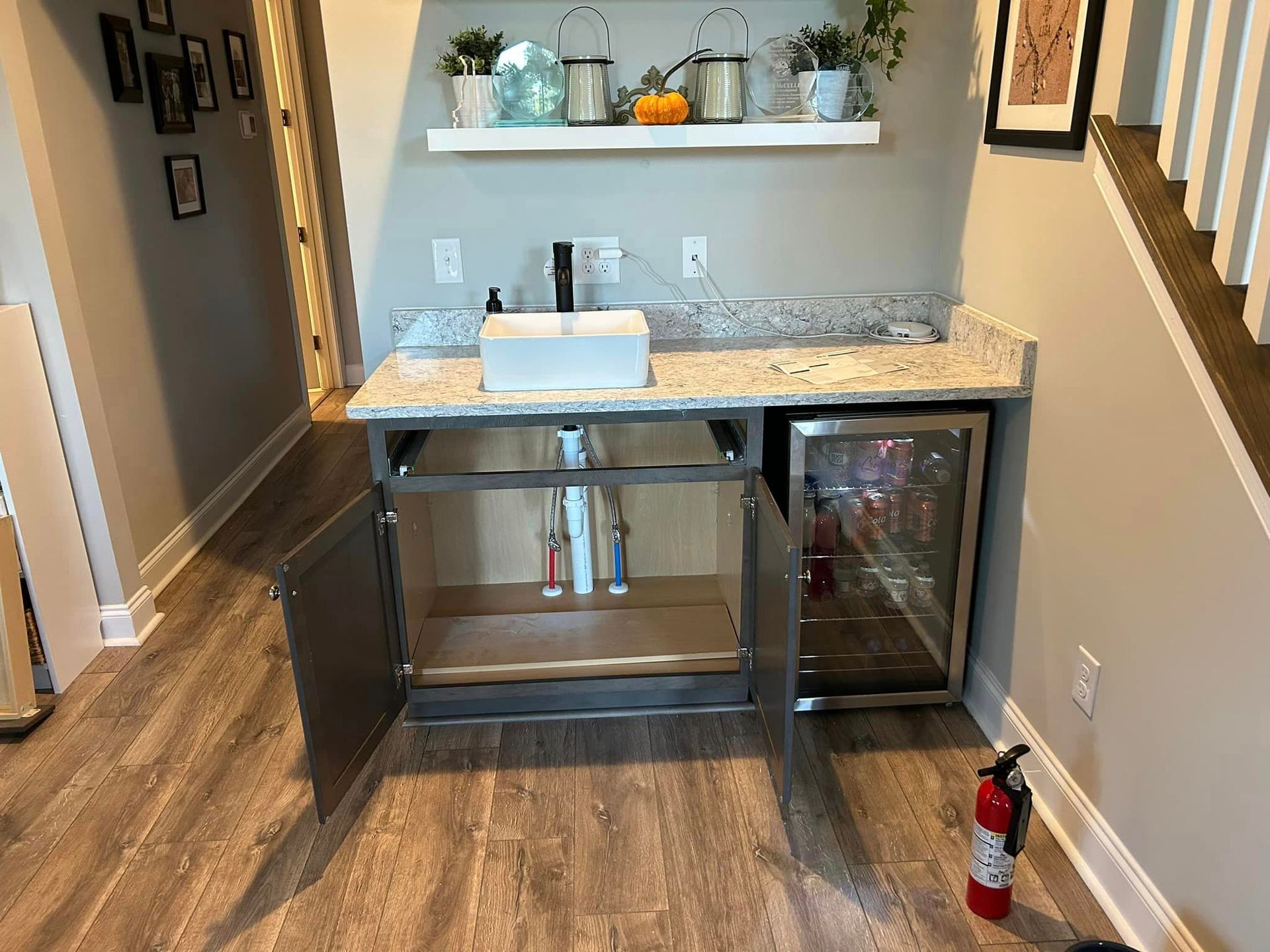 A kitchen with a sink , refrigerator , and fire extinguisher.
