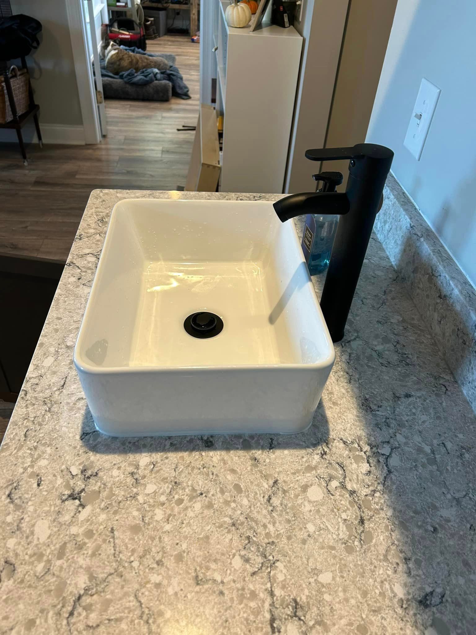 A white sink with a black faucet is on a counter.