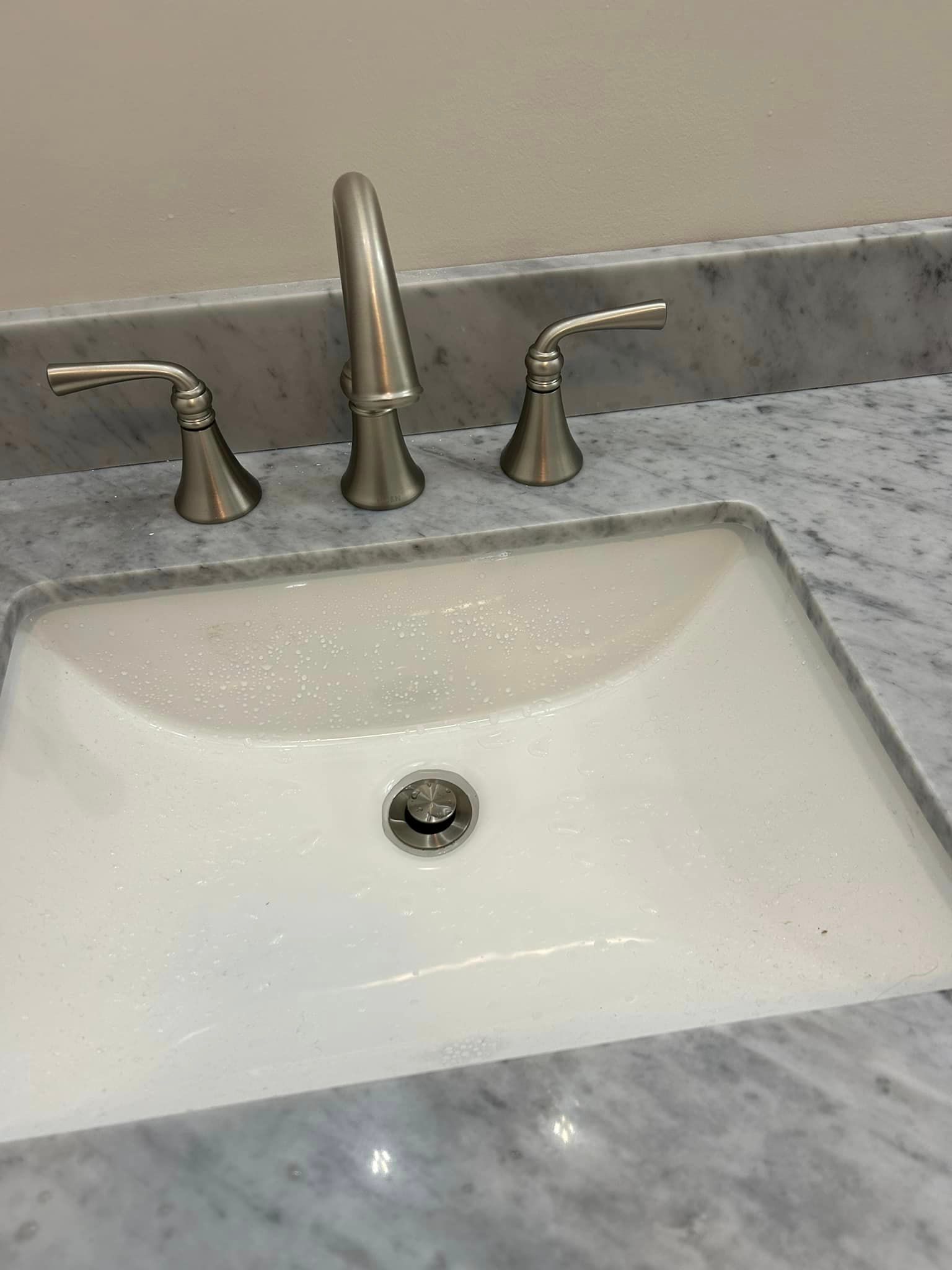 A bathroom sink with a faucet on a marble counter top.