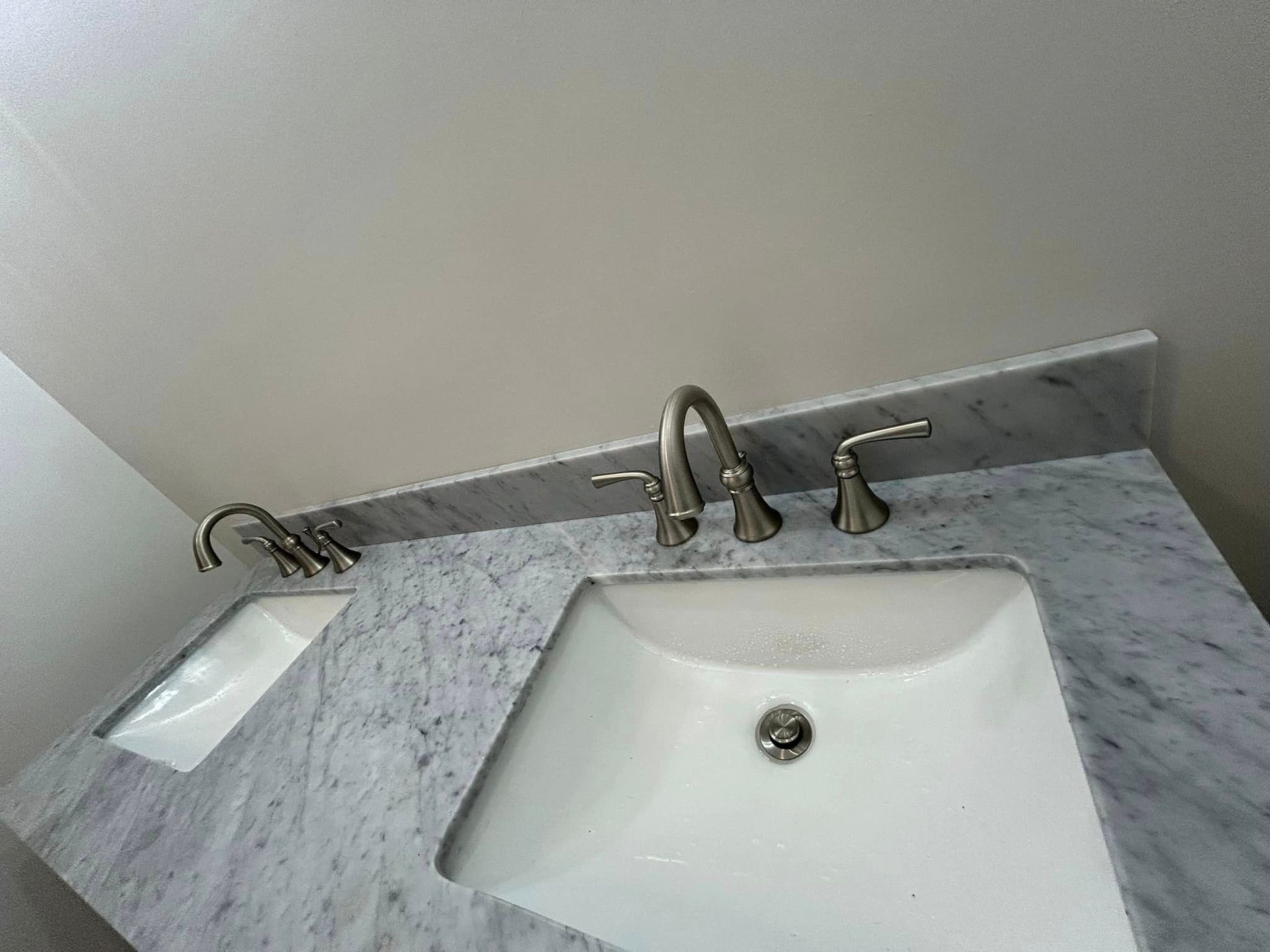 A bathroom sink with two faucets and a mirror.