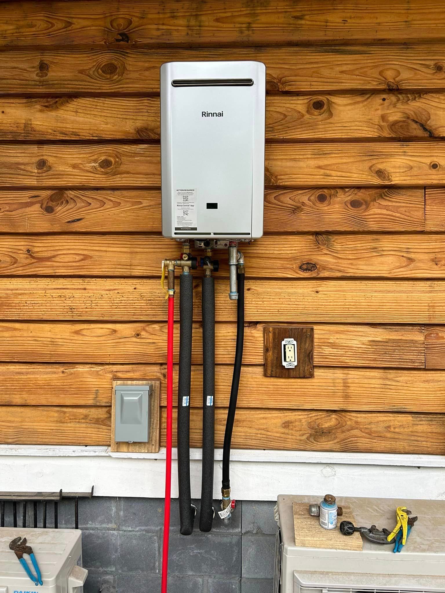 A water heater is attached to a wooden wall.